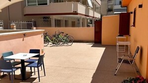 Un patio al aire libre con una mesa, sillas, un sofá, una bicicleta y una butaca.