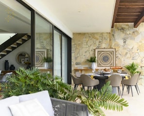 Un espace de salle à manger moderne avec un mur en pierre, un escalier et une table à manger dressée pour six personnes.