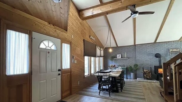 Un interior de madera con comedor, chimenea y ventilador de techo.