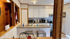 Una cocina moderna con armarios blancos, encimera de granito y una isla central con taburetes de bar.