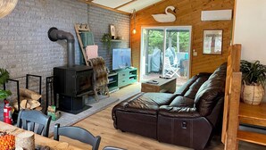 Un salón acogedor con chimenea, sofá de cuero y techo de madera.