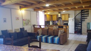 A spacious living area with a sofa set, a dining table, and a kitchen in the background. - Gîte Lavardac Estussan (Lavardac)