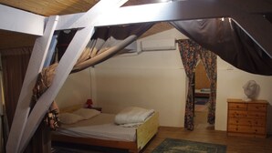 A bedroom with a bed, wooden dresser, and a fan. - Gîte Lavardac Estussan (Lavardac)