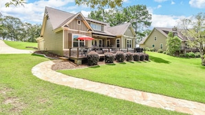 A two-story house with a covered porch, a stone pathway, and a well-maintained lawn.
