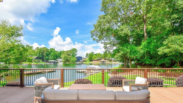 A deck with wicker furniture and a view of a lake.