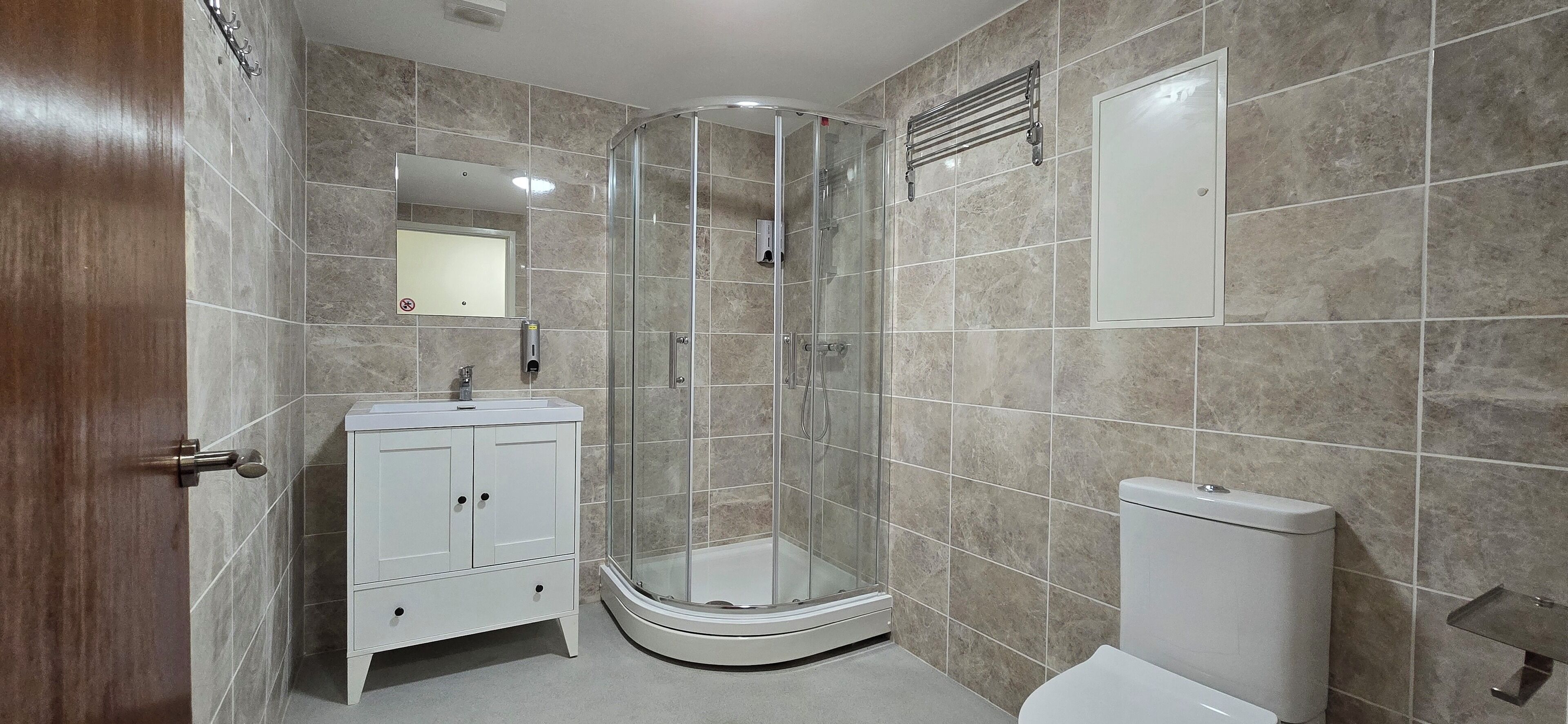 A modern bathroom with a glass-enclosed shower, a white vanity, and a toilet.