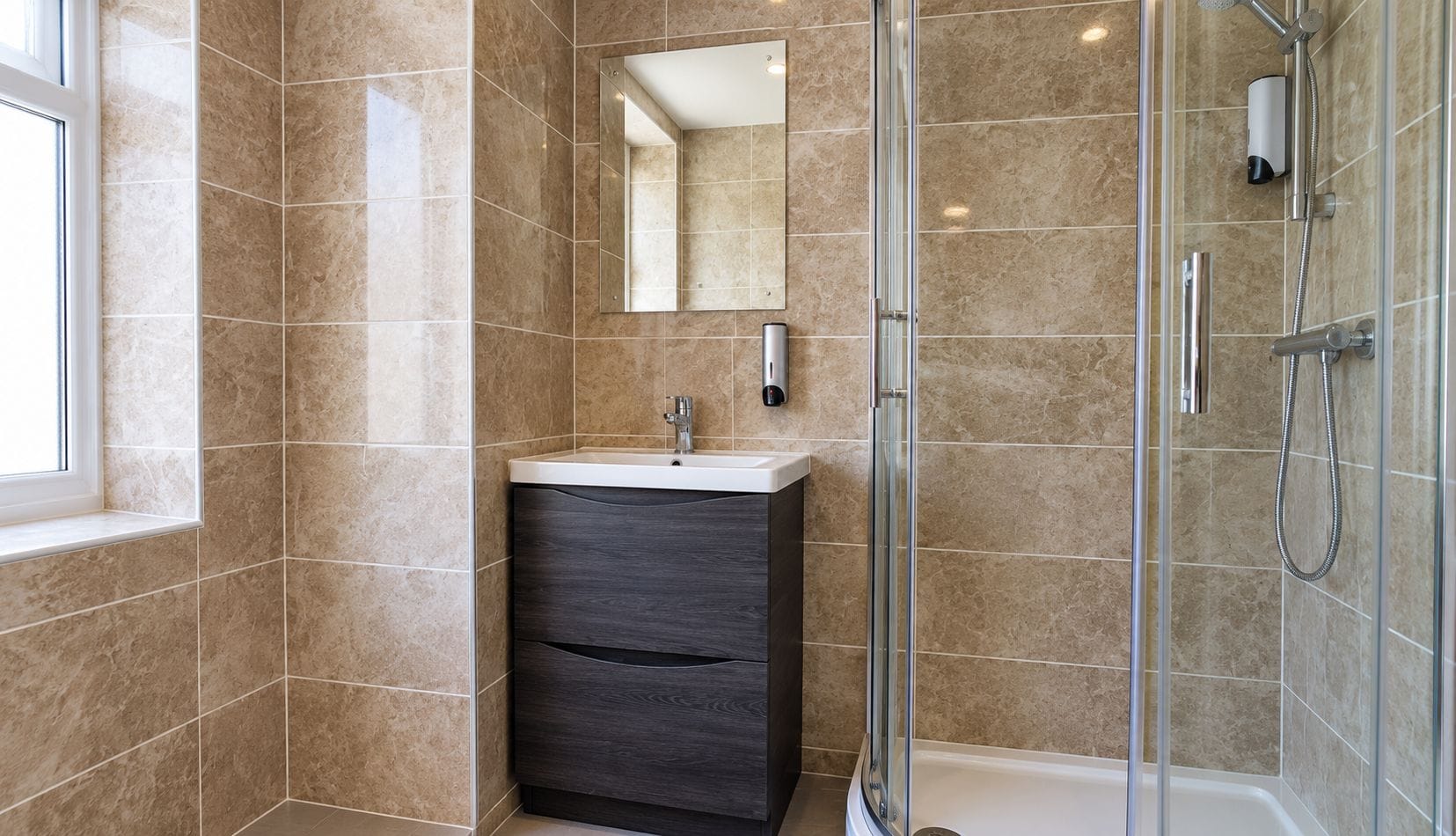 A modern bathroom with a glass shower enclosure, a vanity with a mirror, and a window.