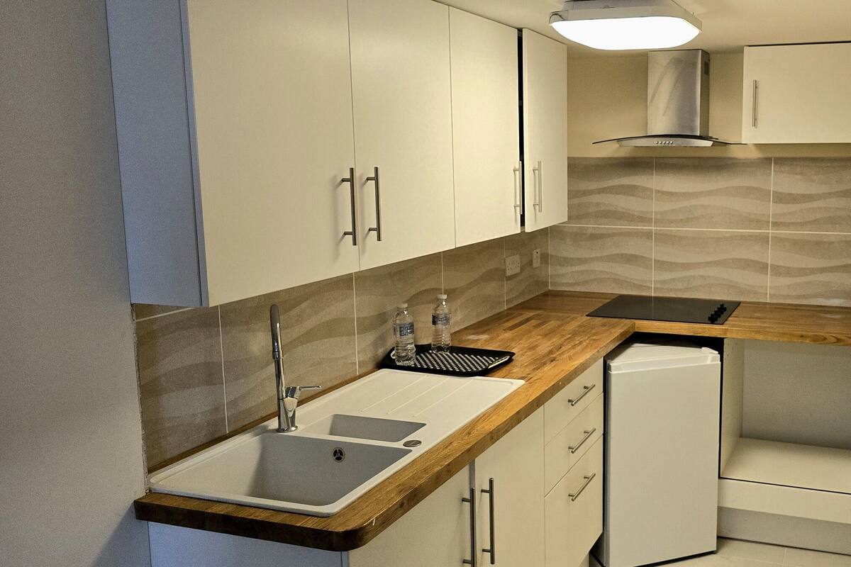A modern kitchen with white cabinets, a wooden countertop, a sink, and a dishwasher.