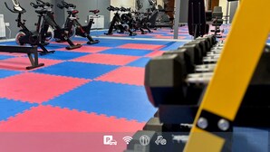 A gym with stationary bikes and treadmills on a checkered floor. - The Carmichael - Hull City Centre (Hull)