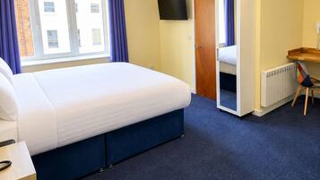 A hotel room with a bed, a desk, a chair, a television, and a door leading to another room.