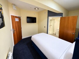 Ein Hotelzimmer mit Bett, Fernseher, Dusche und Tür.