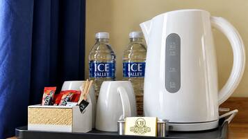 Ontbijtplateau in een hotelkamer met een witte koffiezetapparaat, twee waterflessen, een theezakjeshouder en een klein bordje voor Hotel Carmichael.