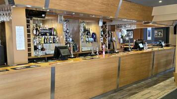 A bar area with a wooden counter, multiple taps, and a variety of bottles.