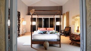 A bedroom with a four-poster bed, a large vase, and a patterned wall. - La Bastide du Farfadet (Laudun)