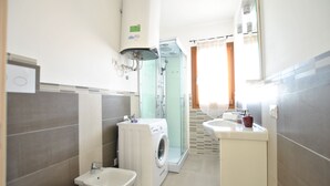 Ein modernes Badezimmer mit Waschmaschine, Bidet und Duschkabine.