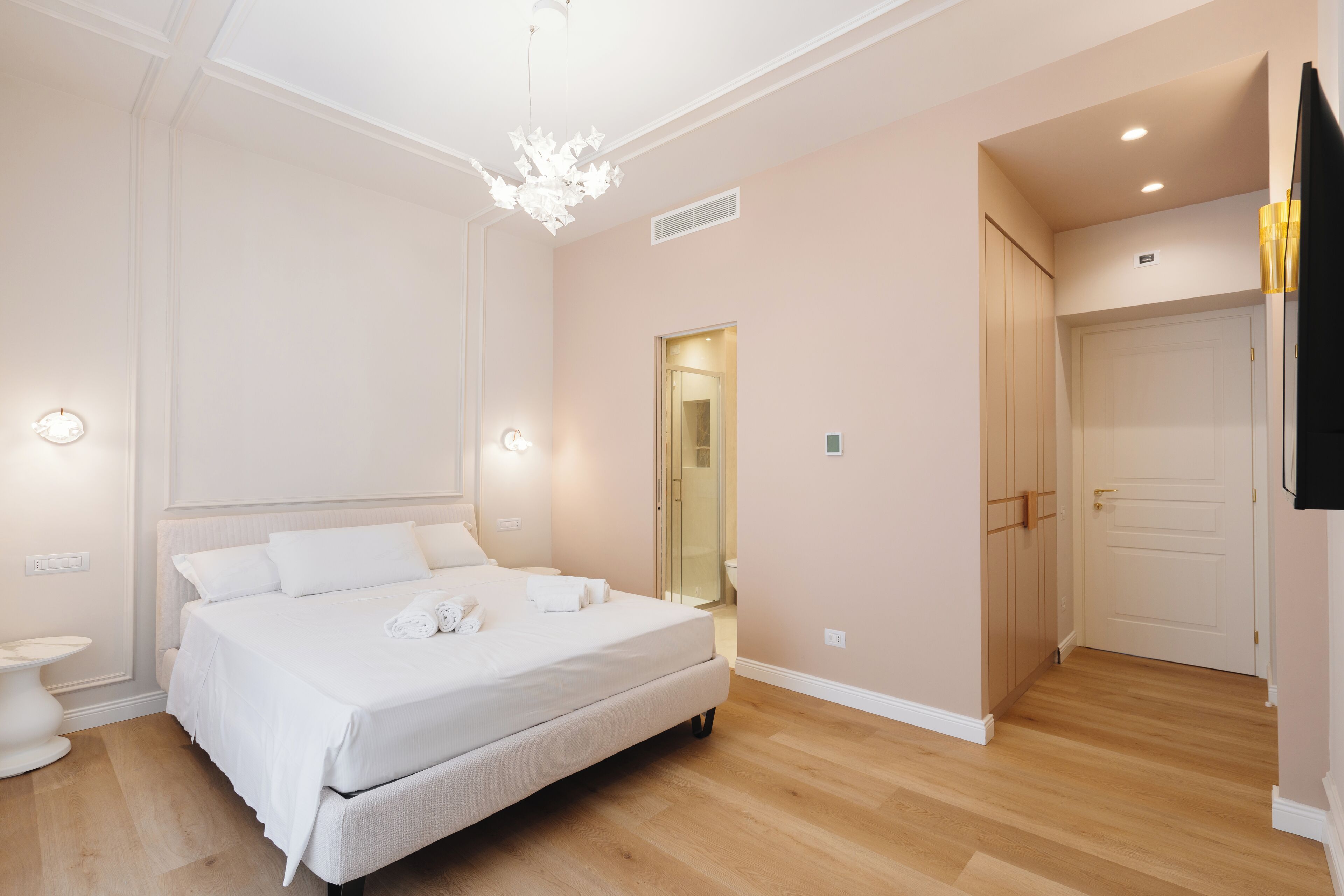 A bedroom with a large bed, bedside tables, a wardrobe, and a bathroom visible through an open door.