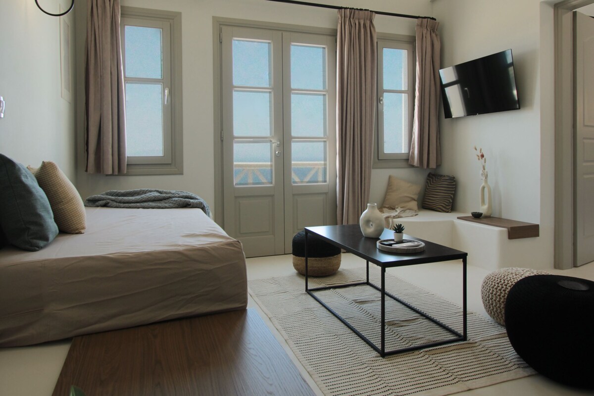 A modern bedroom with a bed, bedside table, and a TV mounted on the wall.