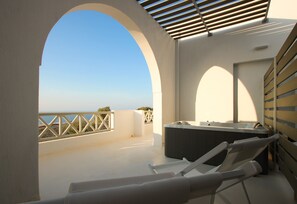 A rooftop terrace with a hot tub, lounge chairs, and a view of the sea. - Airy suites santorini (Santorini)