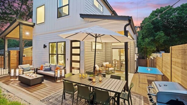 Een modern huis met een terras, buitenmeubels en een barbecue.