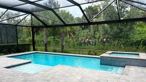 Ein Schwimmbad mit Glaskuppel, umgeben von üppiger Bepflanzung und einer gefliesten Terrasse.