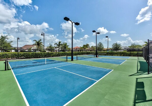 An outdoor tennis court with multiple courts, surrounded by a fence, and equipped with overhead lighting. - Vacation Paradise in Greyhawk gated community, Naples (Naples)
