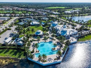 An aerial view of a resort with a central swimming pool, multiple villas, and a body of water. - Vacation Paradise in Greyhawk gated community, Naples (Naples)