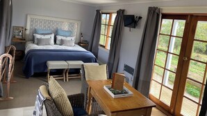Quarto com cama, mesa de cabeceira e vista para o jardim pela janela.