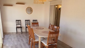 Un comedor con una mesa y sillas de madera, una lámpara colgante y un espejo en la pared.