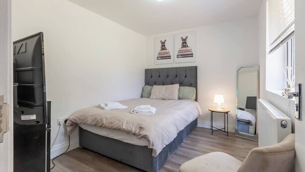 Un dormitorio con una cama, una mesita de noche con una lámpara, una silla y un espejo.