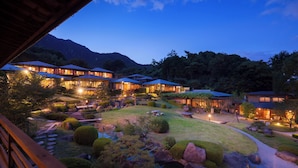 A resort with multiple buildings, well-maintained gardens, and a mountainous backdrop. - Sekitei (Hatsukaichi)
