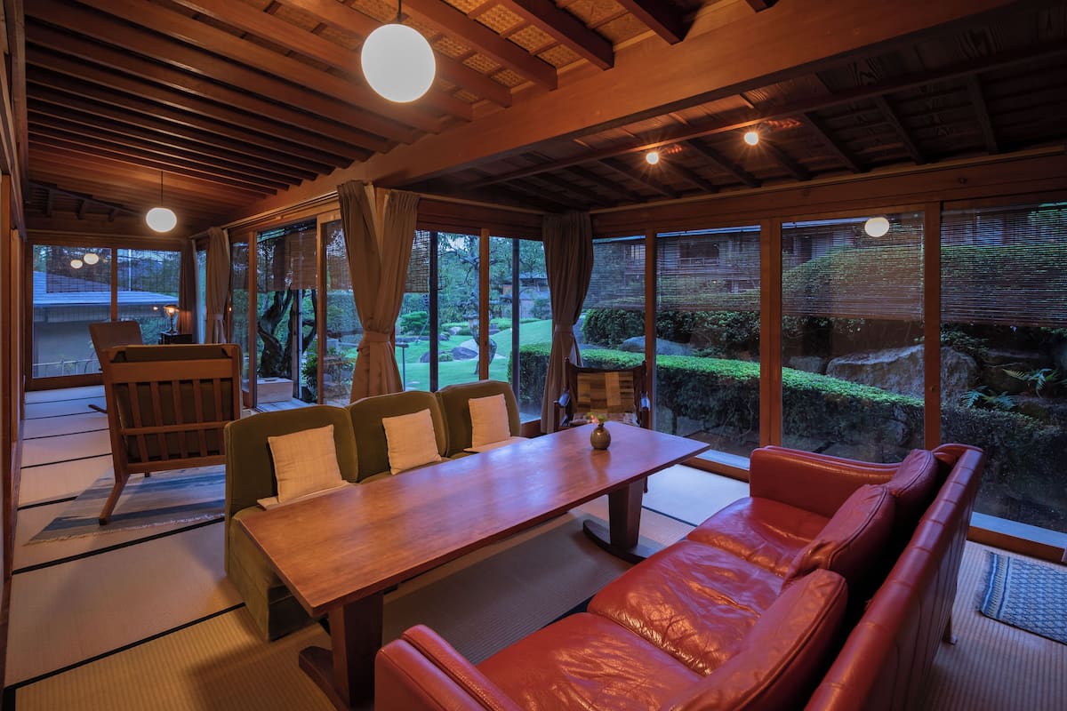 A traditional Japanese-style room with tatami flooring, a wooden dining table, and a sofa.