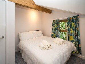 Ein Schlafzimmer mit einem Bett, weißen Laken und gerollten Handtüchern.