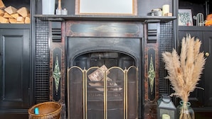 A fireplace with a decorative screen, a framed picture above it, and a vase with pampas grass on the mantel. - Chic Beamish Retreat | Stylish 3-Bed Near Durham - Pass the Keys (Stanley)