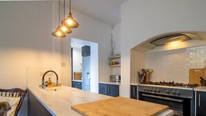 A modern kitchen with a marble countertop, a wooden island, stainless steel appliances, and pendant lighting. - Chic Beamish Retreat | Stylish 3-Bed Near Durham - Pass the Keys (Stanley)