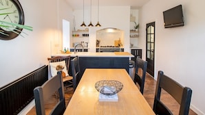 A modern kitchen with a central island, pendant lighting, and a dining area with a wooden table and chairs. - Chic Beamish Retreat | Stylish 3-Bed Near Durham - Pass the Keys (Stanley)