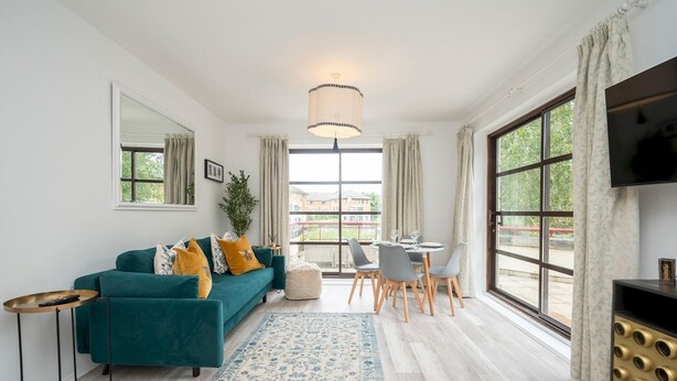 A modern living room with a teal sofa, a small round table, and a TV on a black stand. - London apartment - Waterfront Terrace & Parking - Pass the Keys (London)