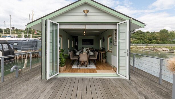 Een overdekt terras met uitzicht op het water en boten.