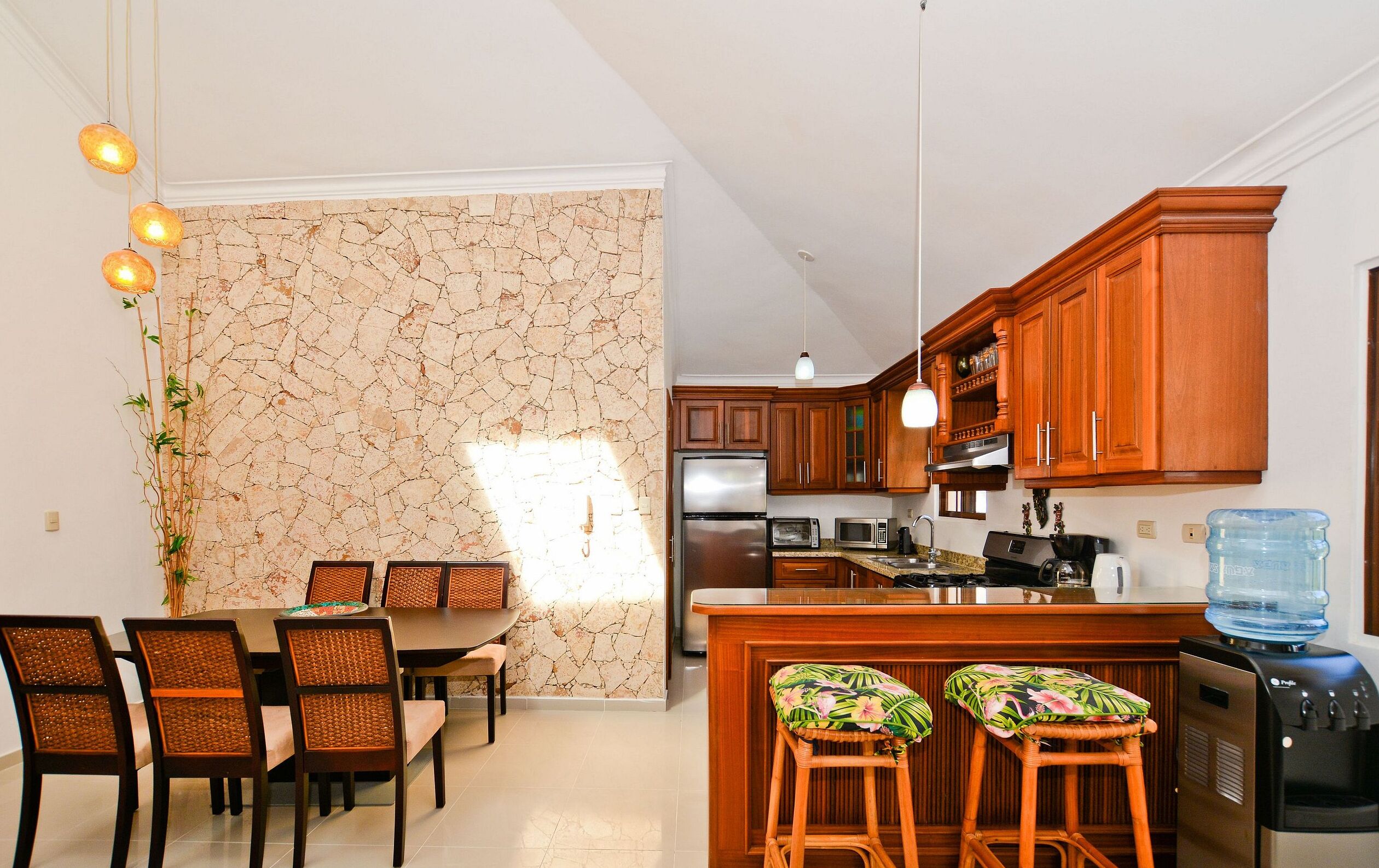 A modern kitchen with wooden cabinets, a stainless steel refrigerator, and a water dispenser.