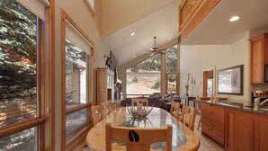 Una cocina amplia con armarios de madera, una mesa de comedor grande y vistas a un área boscosa.