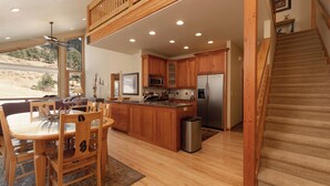 Una cocina amplia con armarios de madera, un refrigerador de acero inoxidable y un comedor con mesa y sillas.