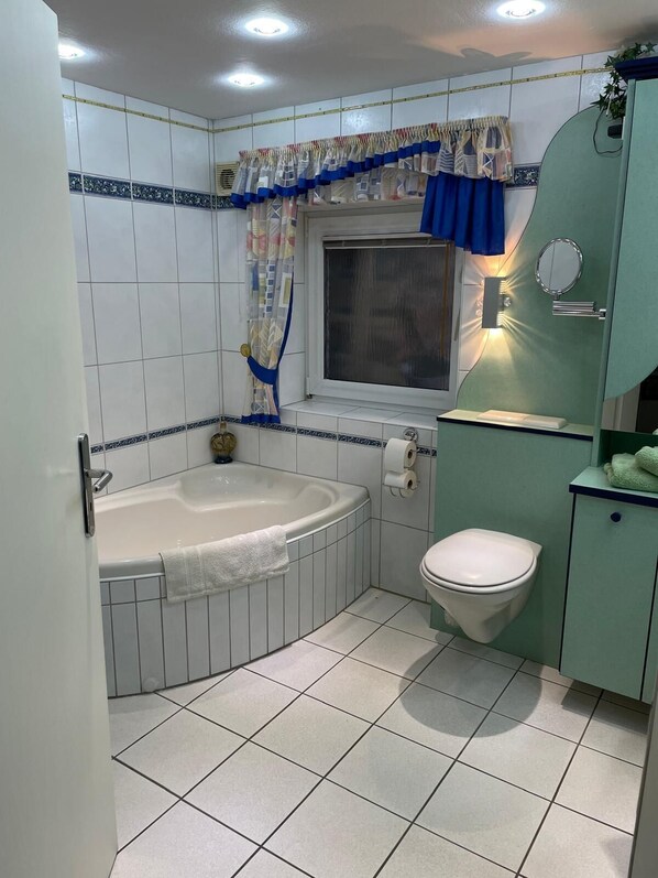Un baño con bañera, inodoro y ventana.