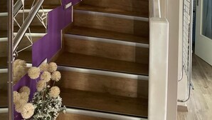 Een meerlaags interieur met een houten trap, paarse accenten en metalen balustrades.