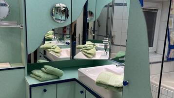 Une salle de bain avec un meuble-lavabo vert, un évier, un miroir et des toilettes.