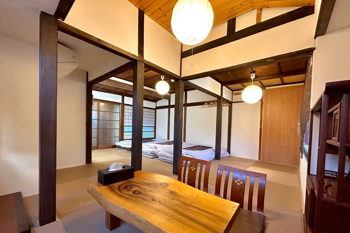 A traditional Japanese-style room with tatami flooring, a low wooden table, and a futon bed.