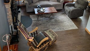 Un salón amplio con un sofá gris, una mesa de centro de madera y una silla de madera original.