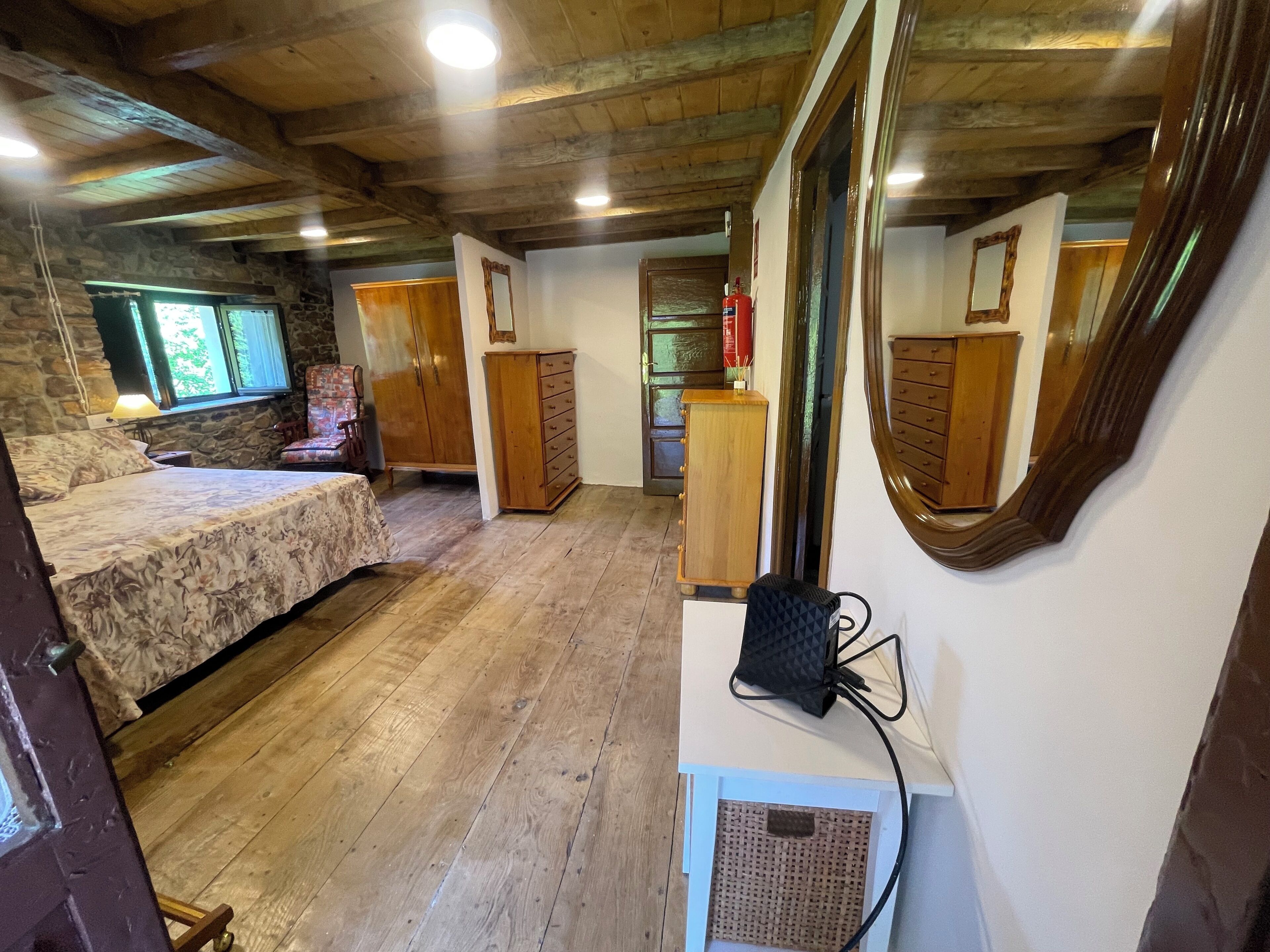 A rustic room with a bed, wooden dresser, and a mirror.