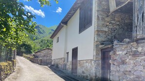 A stone building with a white facade, a door, and a window. - El Pedrosu (Infiesto)