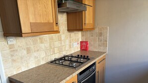 Eine Küche mit Holzausstattung, einem Gasherd, einem Backofen und einer gefliesten Spritzschutzwand.