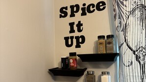 Une cuisine avec des étagères noires où sont rangées différentes épices, et une pancarte sur laquelle on peut lire : « Ajoutez du piquant ! »