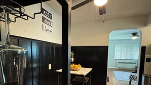 L’intérieur d’un restaurant avec des lambris en bois noir, un ventilateur de plafond, une table sur laquelle se trouve un panier de citrons et un plancher en bois.